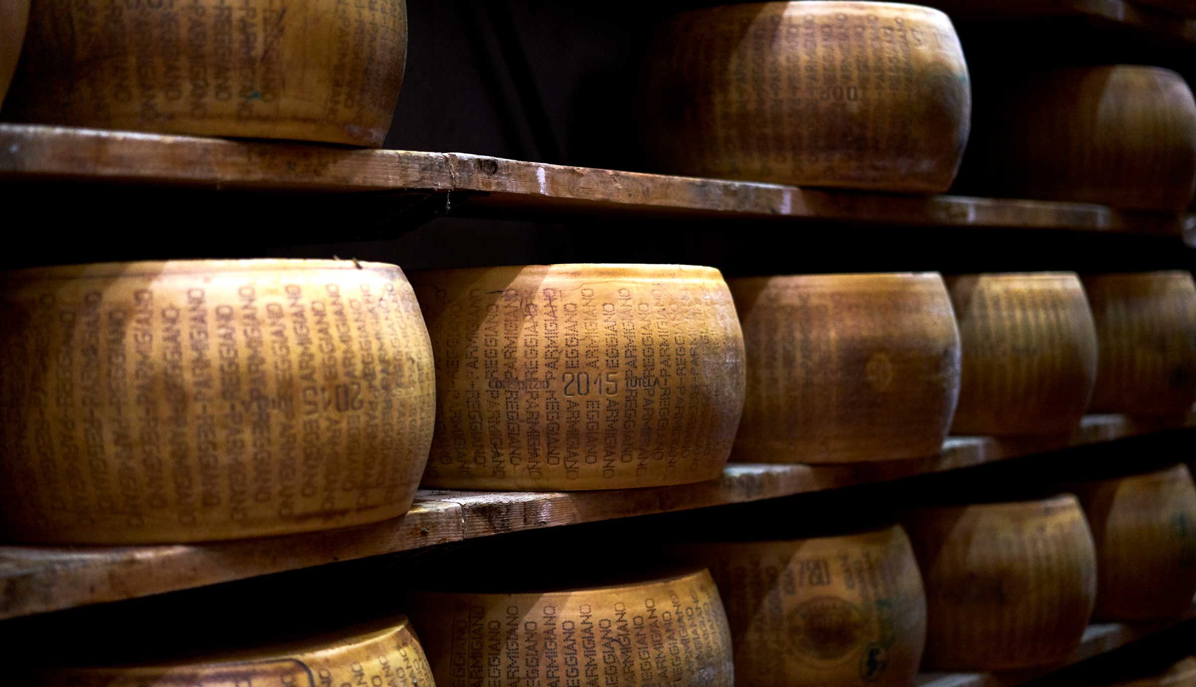 Wheels of Parmigiano Reggiano cheese stacked on shelves